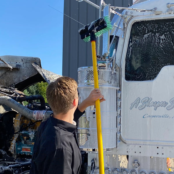 Man using 10" brush to wash semi truck