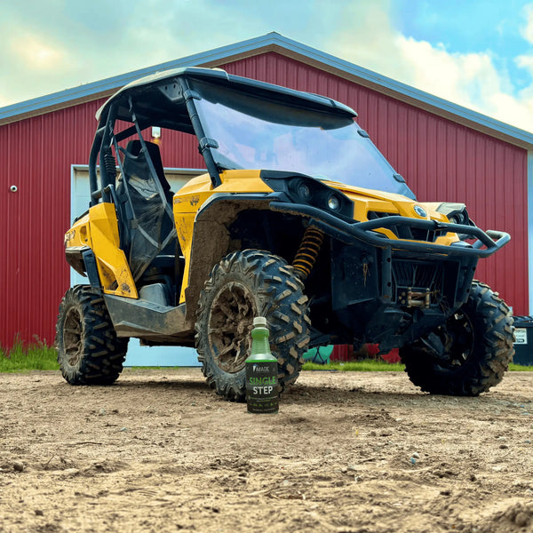 Muddy recreational vehicle parked behing a 32 oz bottle of Image Wash Single Step, a heavy duty atv foam wash
