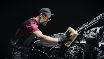 A man washing a car with soap and a sponge