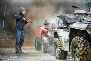 Man cleans ATV with heavy duty equipment washer 