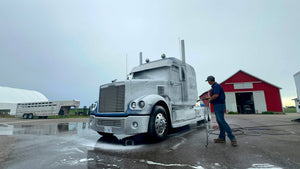 Todd founder of Image Wash Products washing a blue semi truck on a farm.