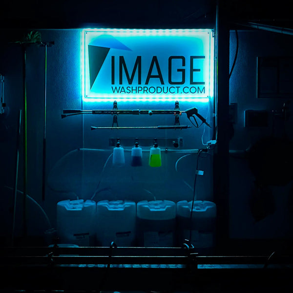 Dark room with illuminated sign displaying 'IMAGE WASHPRODUCT.COM' and cleaning supplies.