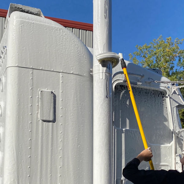 Man using stack brush to clean exhaust stack of semi truck