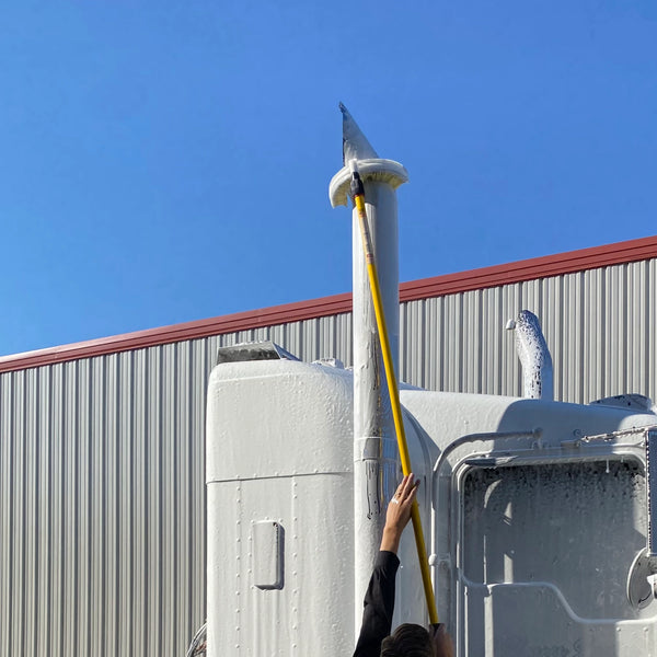 Man using stack brush to clean exhaust stack of semi truck