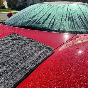 Freshly washed red sports car being dried with a Guantlet drying towel from Image Wash Products.